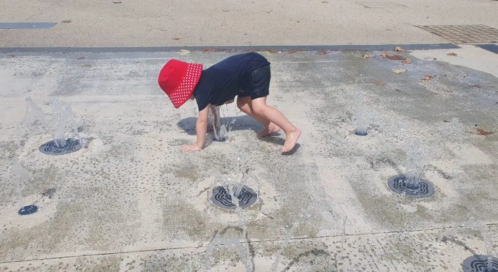Child playing in water fountain